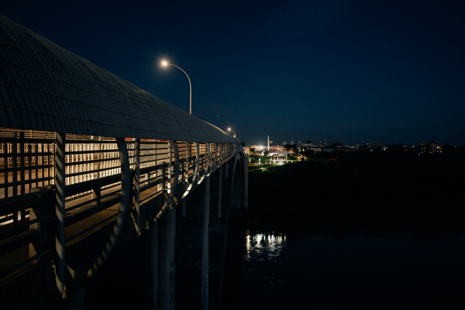 Pasarela iluminada sobre el río en entorno nocturno
