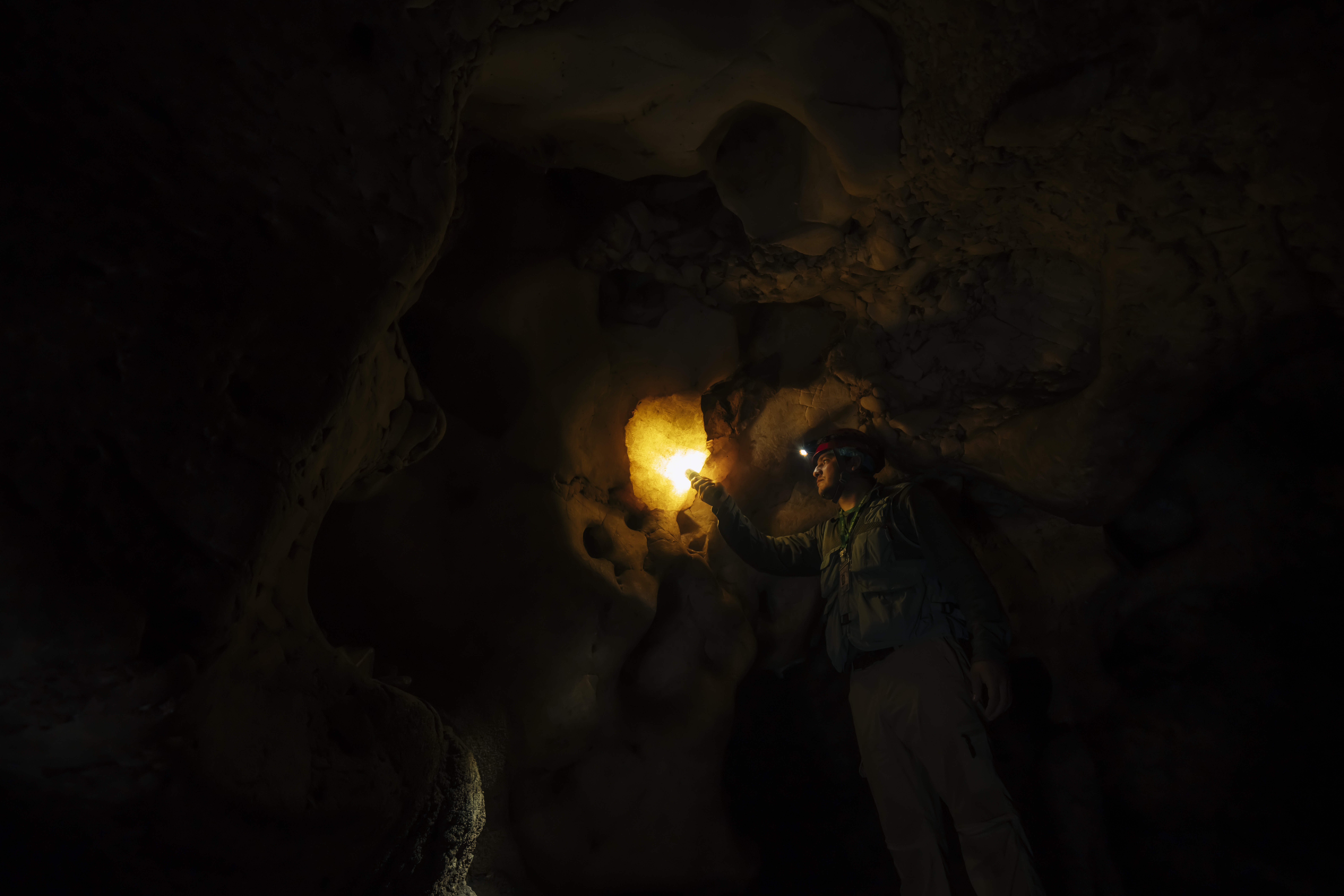 Explorador iluminando formaciones dentro de una caverna