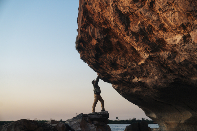 Explorador enfrentando una formación rocosa al atardecer